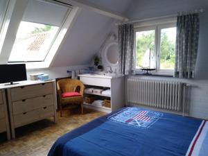 a bedroom with a bed and a desk and windows at Albatros in Koksijde