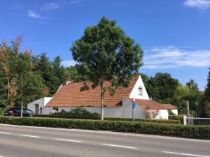 a white house with a tree in front of a street at Albatros in Koksijde