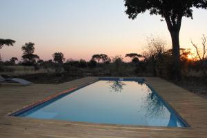 an empty pool on a wooden deck with the sunset in the background at Tlouwana Camp in Kasane