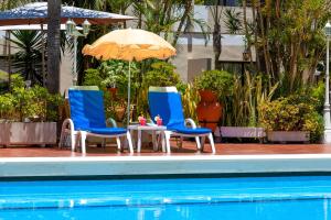 twee stoelen en een parasol naast een zwembad bij Hotel Don Manolito in Puerto de la Cruz