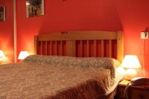 a bedroom with a bed with red walls and two lamps at Logis Hôtel et Restaurant La Tour Brette in Pontorson