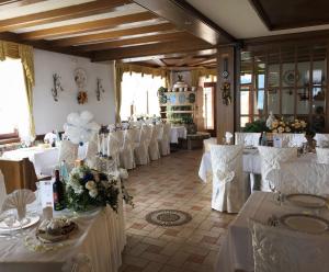 una stanza piena di tavoli e sedie con biancheria da tavolo bianca di HOTEL RISTORANTE SCOIATTOLO a Sporminore