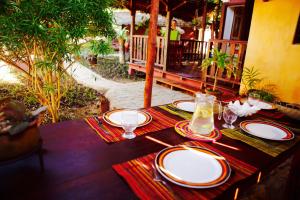 a table with plates and glasses on top at Hotel Ambalamanga in Nosy Be