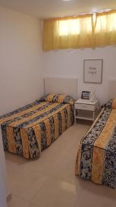 a bedroom with three beds and a table in it at Las Algas 1 Etage in Maspalomas