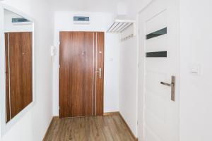 a hallway with a wooden door and white walls at Apartament Smętka in Olsztyn