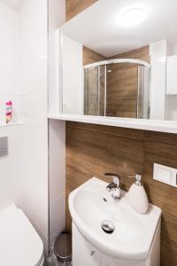 a white bathroom with a sink and a mirror at Apartament Smętka in Olsztyn