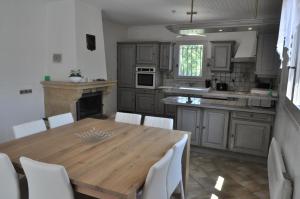 - une cuisine avec une table en bois et des chaises blanches dans l'établissement Les Prairies de l'Encrême, à Céreste