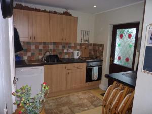 a kitchen with wooden cabinets and a sink and a stove at Banfield Lodge for Gower in Swansea