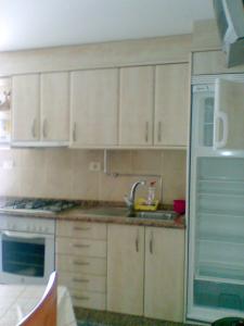 una cucina con armadi bianchi, lavandino e frigorifero di Casa de la Abuela a Bubaces