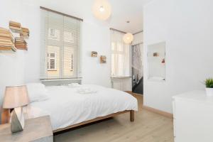 a white bedroom with a white bed and windows at Apartments Poznań Strzałowa by Renters in Poznań