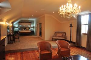 a living room with a bed and chairs and a chandelier at Kearsney Manor in KwaDukuza