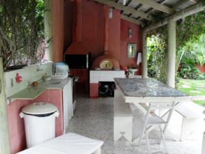an outdoor kitchen with a table and a stove at Chalés Musa de Maresias in Maresias