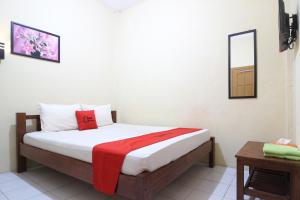 um quarto com uma cama com um cobertor vermelho em RedDoorz @ Jalan Parangtritis em Yogyakarta