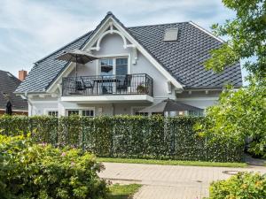 ein weißes Haus mit einem Zaun und einem Balkon in der Unterkunft Haus MEERLE in Zingst