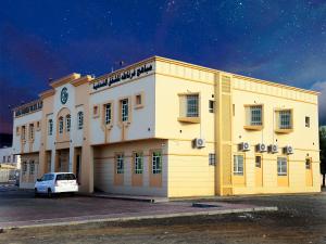 a white car parked in front of a building at Mabahj Garnatha Hotel Apartments in Sohar