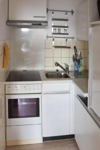 a white kitchen with a sink and a stove at Freiwasser Appartment in Glücksburg