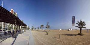 a sandy beach with palm trees and a building at Apartamentos Turisticos Biarritz - Bloque I in Gandía