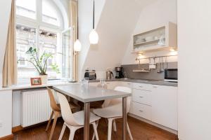kuchnia z białymi szafkami, stołem i krzesłami w obiekcie Apartments Poznań Strzałowa by Noclegi Renters w Poznaniu