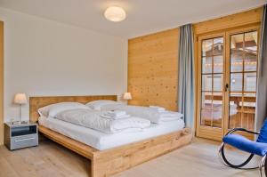 1 dormitorio con 1 cama grande y pared de madera en Apartment Bränderli - GRIWA RENT AG en Grindelwald