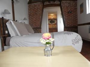 L'Etape Normande في Montroty: إناء من الزهور على طاولة في غرفة النوم