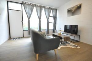 a living room with a chair and a television at The One @ Henley Beach in Grange