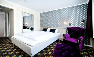 um quarto com uma cama branca e uma cadeira roxa em Havila Hotel Raftevold em Hornindal