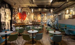 un ristorante con tavoli e sedie e graffiti alle pareti di Link Hotel & Hub By Dan Hotels a Tel Aviv