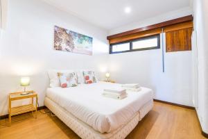 a white bedroom with a bed and a window at Carcavelos Beach & Business by The Portuguese Butler in Carcavelos