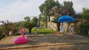 un parque infantil con un flamenco rosa, sillas y una sombrilla en La fattoria di nonna elvira, en Belvedere Marittimo