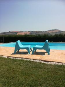 2 bancs bleus assis à côté d'une piscine dans l'établissement Il Gallo Del Vicino, à Monte Urano