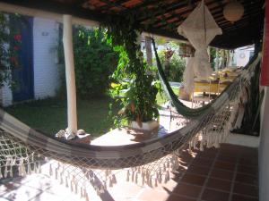 a hammock in a patio with a table and chairs at Pousada Ancora in Vera Cruz de Itaparica