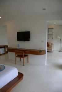 a bedroom with a bed and a tv on a wall at Montalay Beach Resort - SHA Plus in Ko Tao