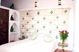 a bedroom with a white bed with a wall at Riad Ben Youssef in Marrakech