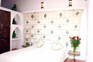 a bedroom with a white bed with a wall at Riad Ben Youssef in Marrakesh