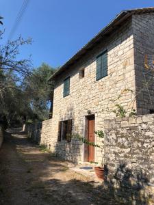 a stone building with a red door and a stone wall at The "M" House in Gaios