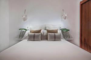 un letto bianco con quattro cuscini in una stanza di Maspalomas Suites a Maspalomas Altre 20 foto