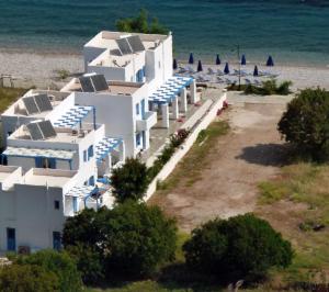 Dream Island Hotel في Livadia: مجموعة من المباني البيضاء على شاطئ به مظلات