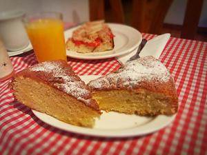 dos rebanadas de pastel en un plato en una mesa con zumo de naranja en Casa Úrsula, en Ansó