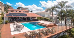 a house with a swimming pool and a deck with chairs at Pousada Suítes do Lago in Capitólio
