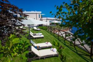 a group of lounge chairs with umbrellas on the grass at Villa Paradise Resort in Agerola