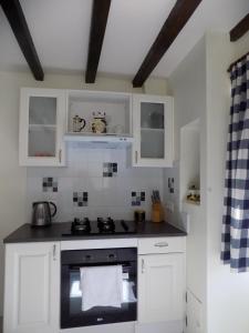 a kitchen with white cabinets and a stove top oven at Aux Roses in Vrolle
