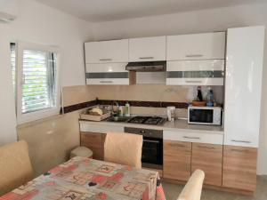 a kitchen with white cabinets and a table and a microwave at Apartments Mira in Velike Kuknjare