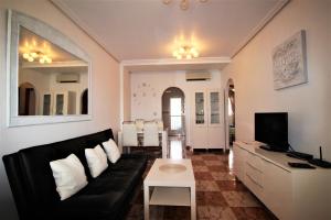 salon z czarną kanapą i telewizorem w obiekcie Best House Rubi w mieście Playas de Orihuela