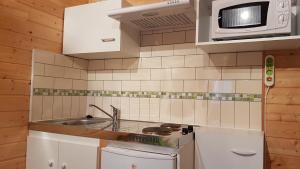 una pequeña cocina con fregadero y microondas en Bungalow de Kermoal en Trébrivan
