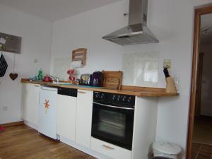 a kitchen with white cabinets and a black oven at The little Stone House in Blankenheim