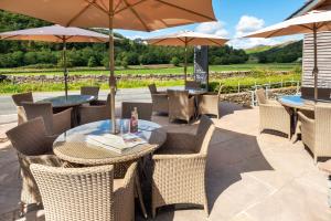 a patio area with tables, chairs and umbrellas at The Lodge In The Vale in Legburthwaite