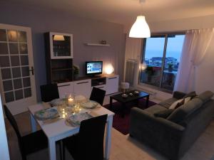 a living room with a table and a couch and a television at Phare Ouest Amirauté in Pléneuf-Val-André
