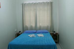 a bedroom with a blue bed with two towels on it at Hotel Guarany in Canoinhas