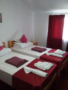 Dos camas en una habitación con toallas rojas y blancas. en Pensiunea Magura, en Baia de Fier