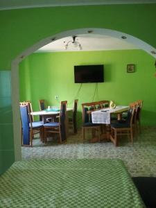 a dining room with green walls and a table and chairs at Pensiunea Magura in Baia de Fier